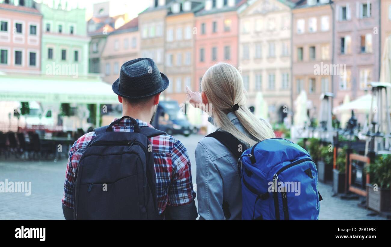 Vue arrière de jeunes touristes couple avec des sacs vérifier la carte sur la place centrale de la ville. Ils discutent de leur nouvelle destination. Banque D'Images