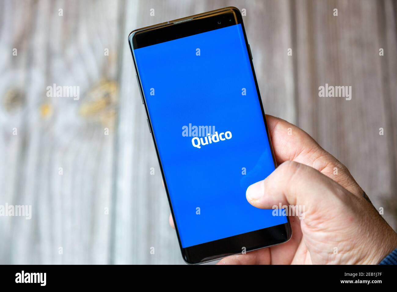 Un téléphone mobile ou mobile détenu par un Main avec l'application Quidco ouverte à l'écran Banque D'Images