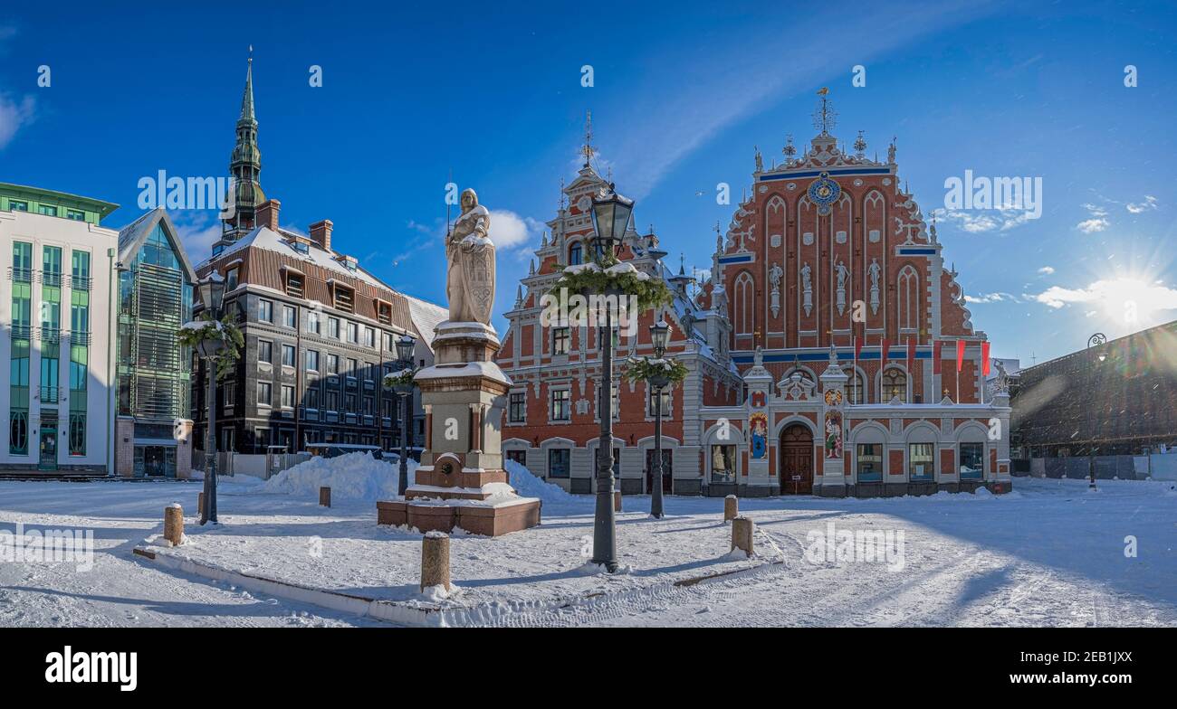 Place de l'hôtel de ville pendant la journée ensoleillée de neige en hiver à Riga, en Lettonie. Vue sur la maison enneigée des Blackheads et la statue de Roland dans la vieille ville de Riga. Banque D'Images
