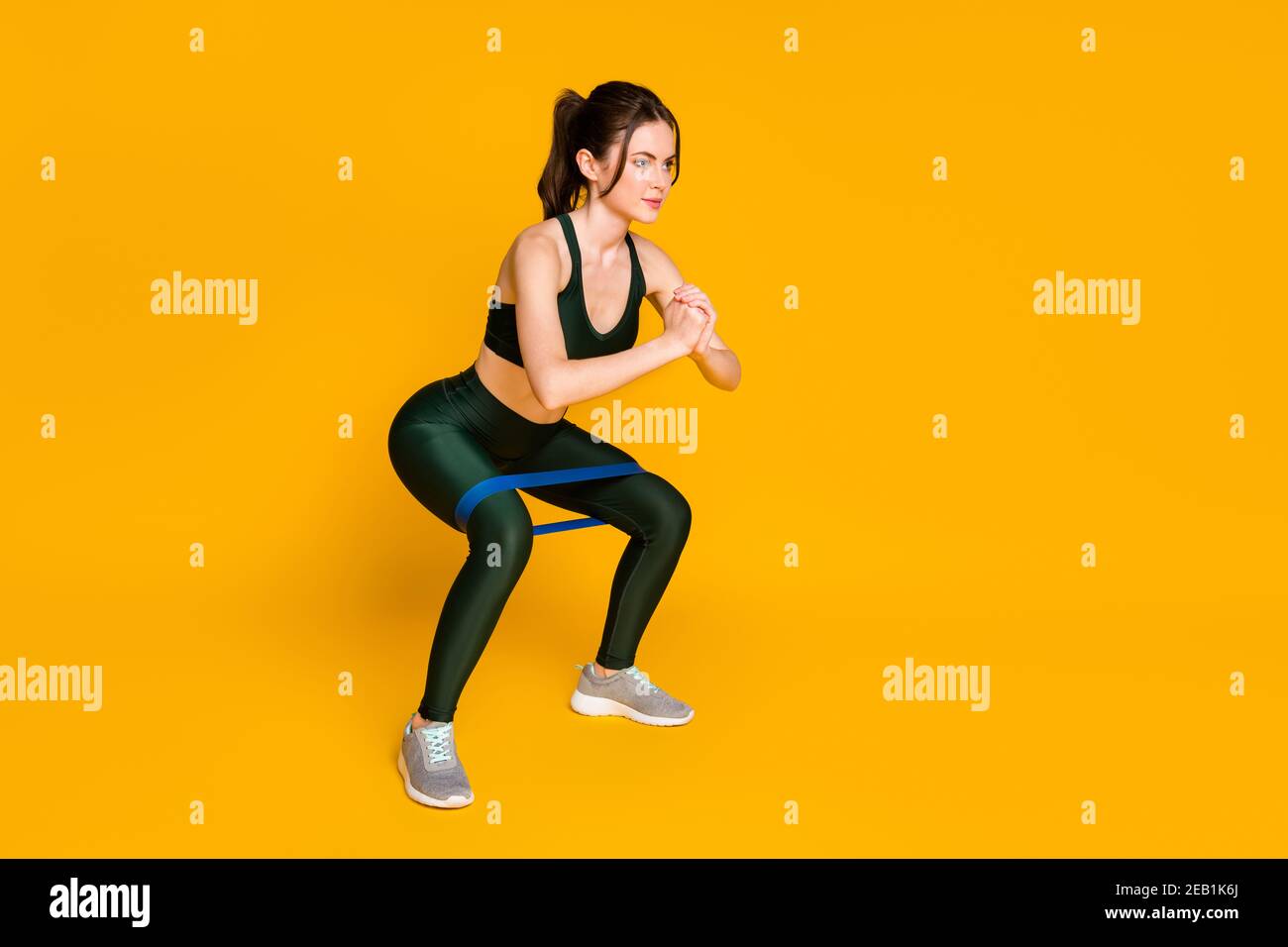 Jeune femme maison gym entraînement stretch résistance rayures faire des  squats porter un costume de sport isolé de couleur jaune fond Photo Stock -  Alamy