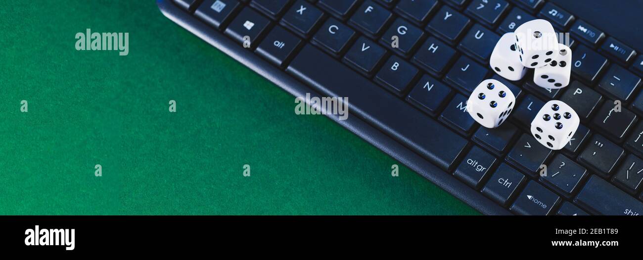 Plate-forme de jeu en ligne, casino et affaires de jeu. Dés sur le clavier de l'ordinateur portable sur fond vert. Banque D'Images