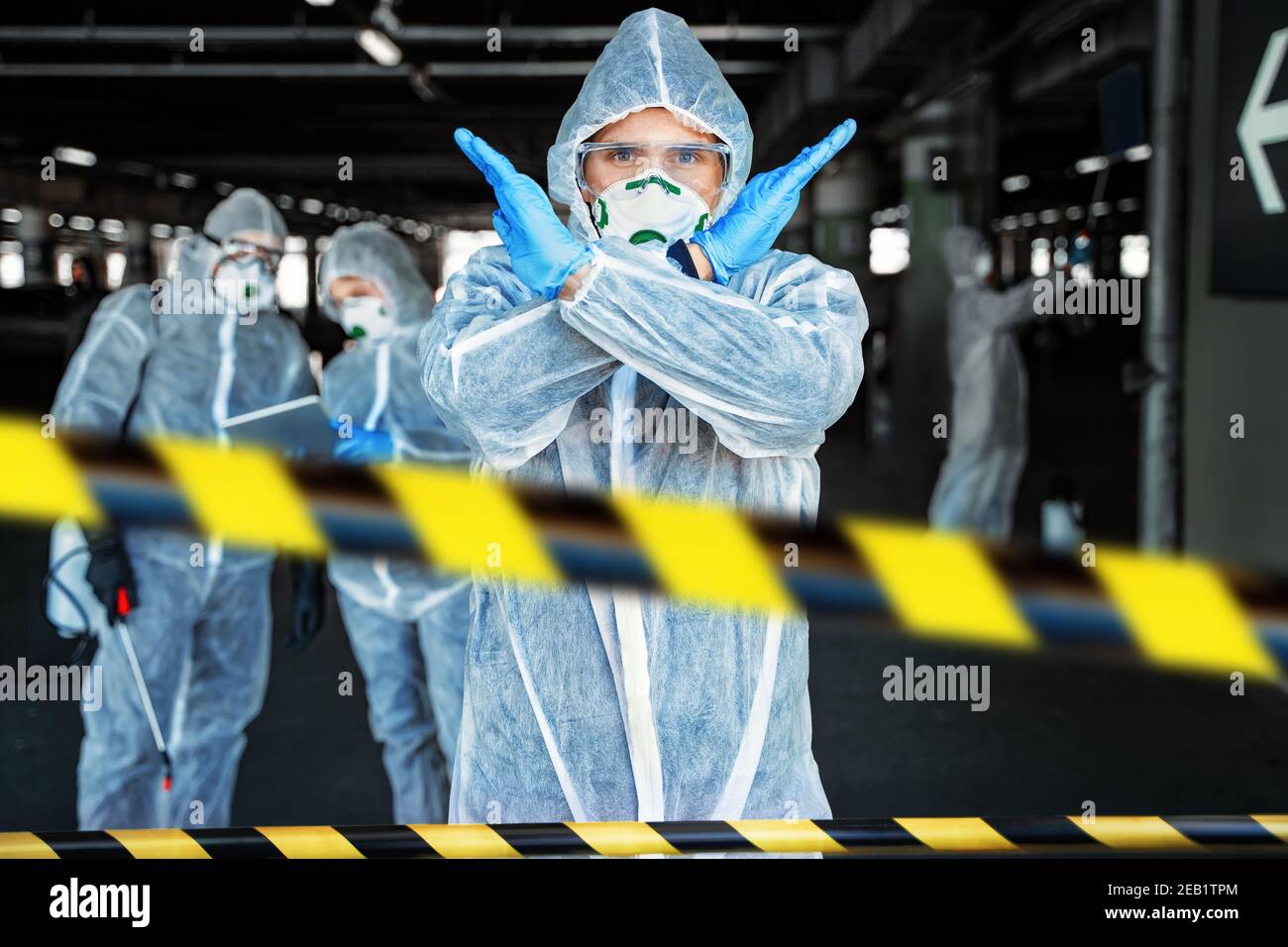 Professionnel de santé montrant un geste d'arrêt. Une équipe de professionnels de la santé portant des combinaisons de matières dangereuses travaille ensemble pour contrôler une épidémie dans la ville Banque D'Images