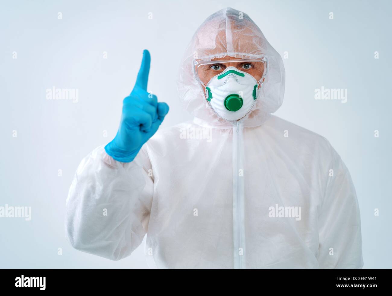 Professionnel de la santé en costume de protection et masque médical pointant vers le haut du doigt. Concept de soins de santé. Banque D'Images