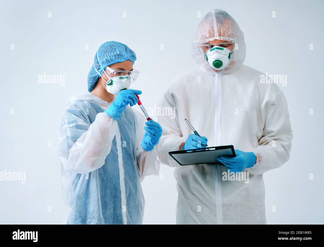 Le médecin tient le presse-papiers et l'infirmière affiche le résultat du test sanguin. Travailleurs de la santé en combinaisons de protection et masques médicaux Banque D'Images