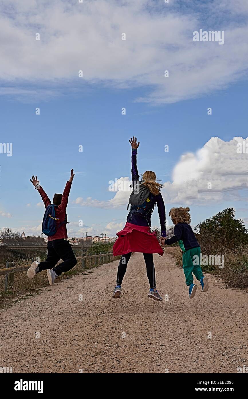 Jeune femme blonde avec deux enfants sautant. Caucasien, sportswear, ciel bleu , style de vie, heureux Banque D'Images