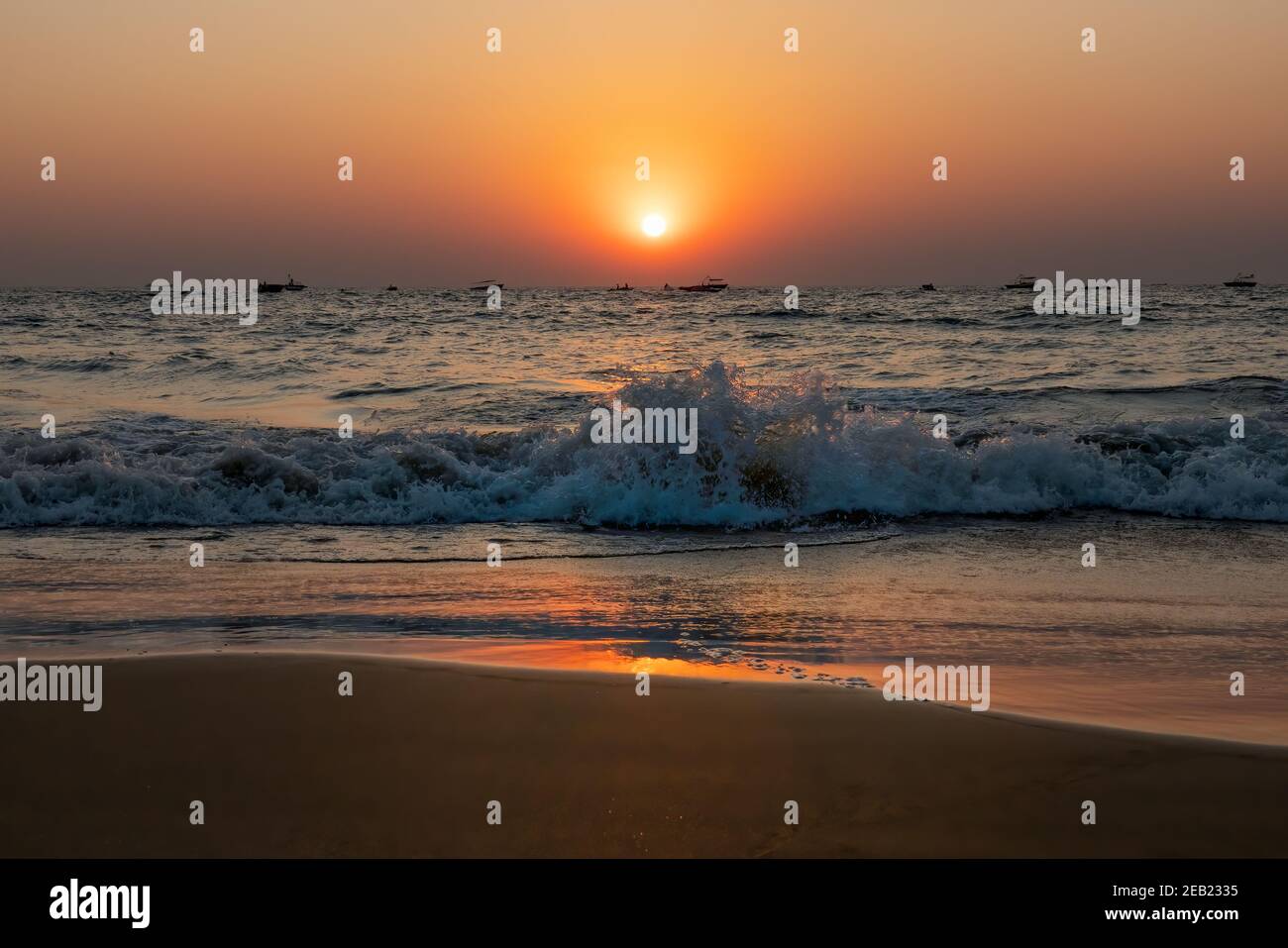 Coucher de soleil pittoresque sur la plage en Asie du Sud, vague blanche sur la côte sablonneuse. Beaucoup de bateaux de pêche sur la ligne d'horizon dans l'océan Indien. Ciel clair du soir être Banque D'Images