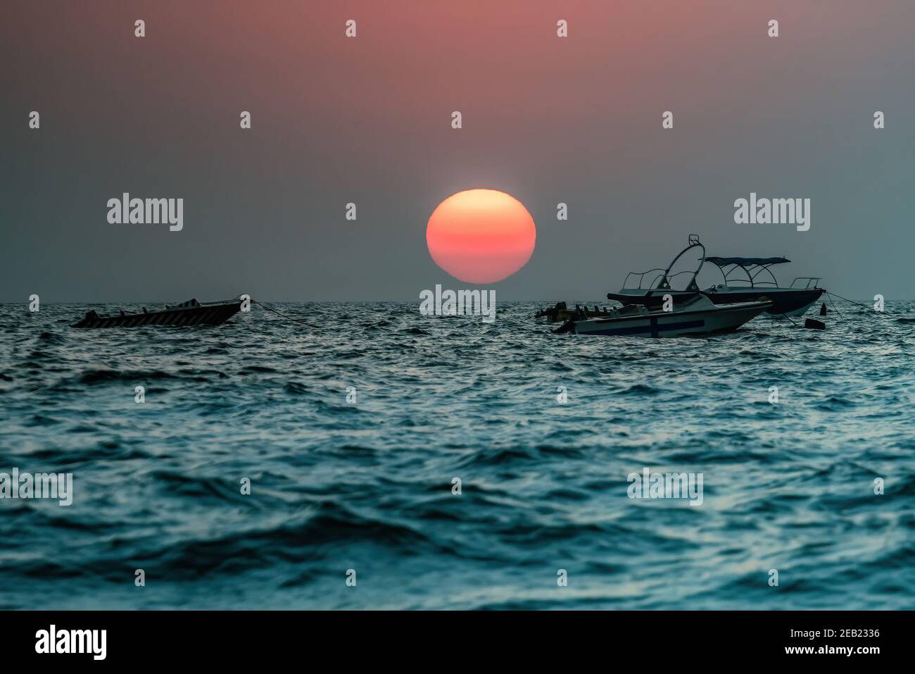 Fermer Scenic Sunset sur la plage en Asie du Sud ? Bateaux de pêche sur la ligne d'horizon dans l'océan Indien. Ciel clair de soirée magnifiquement mis en évidence par grand orange r Banque D'Images