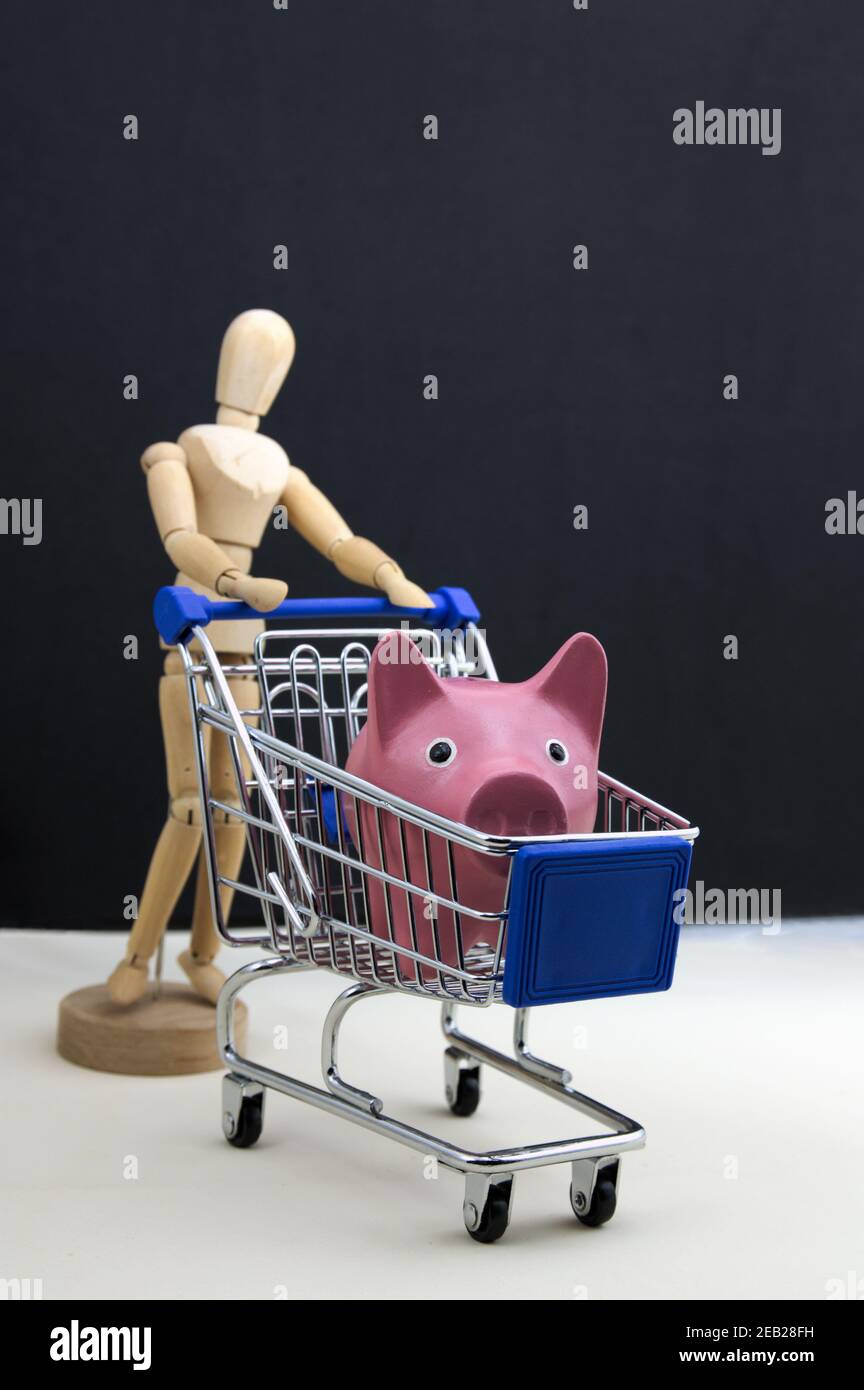 Un mannequin porte un chariot dans lequel il porte une banque de porc rose pour faire du shopping Banque D'Images