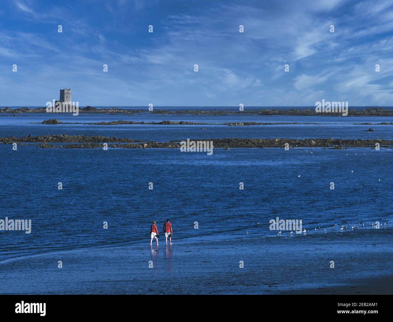 Seymour Tower en arrière-plan que les visiteurs marchent le long du rivage, Jersey, Channel Islands. Banque D'Images