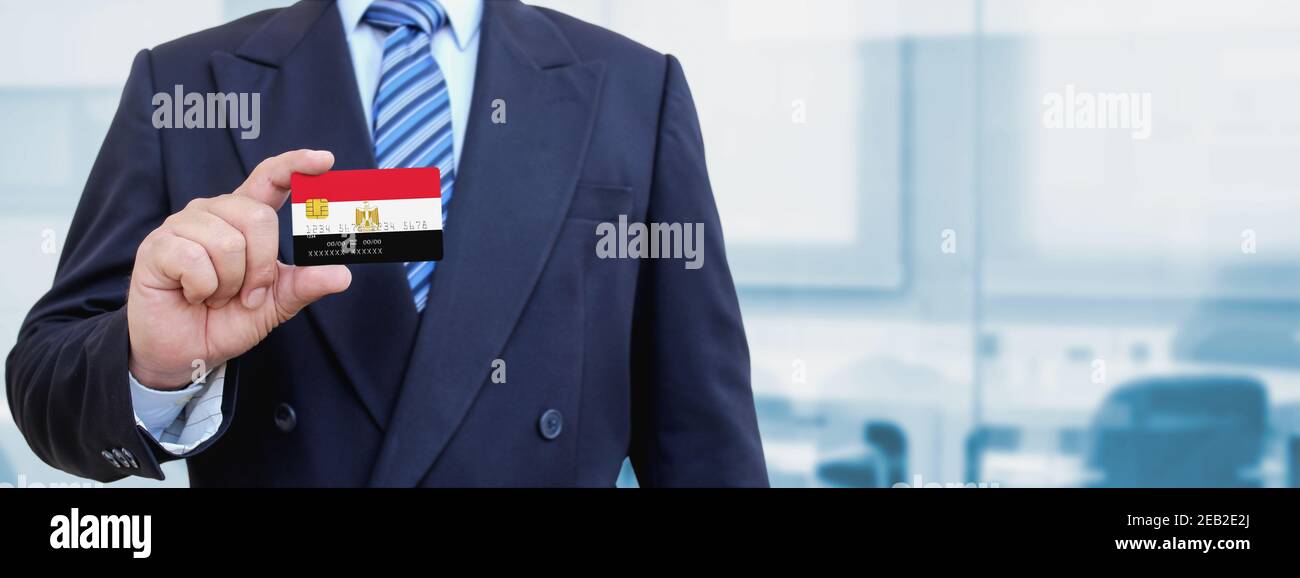 Image rognée d'un homme d'affaires tenant une carte de crédit en plastique avec drapeau imprimé de l'Égypte. Arrière-plan flou. Banque D'Images