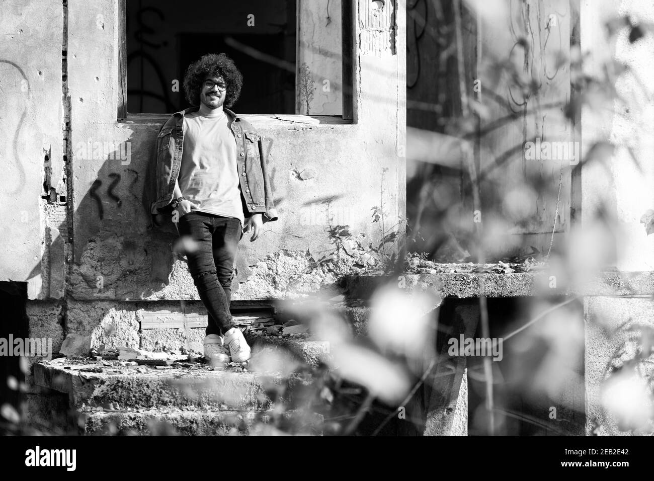 Portrait d'un jeune homme cheveux afro posant à abandonné Maison à l'extérieur Banque D'Images