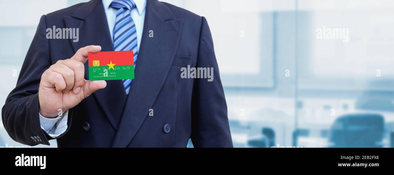 Image rognée d'un homme d'affaires titulaire d'une carte de crédit en plastique avec drapeau imprimé du Burkina Faso. Arrière-plan flou. Banque D'Images