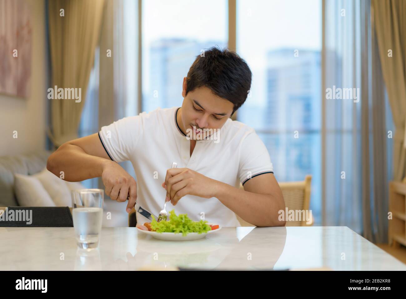 Un homme asiatique prend un petit-déjeuner américain dans le salon de la maison. Banque D'Images