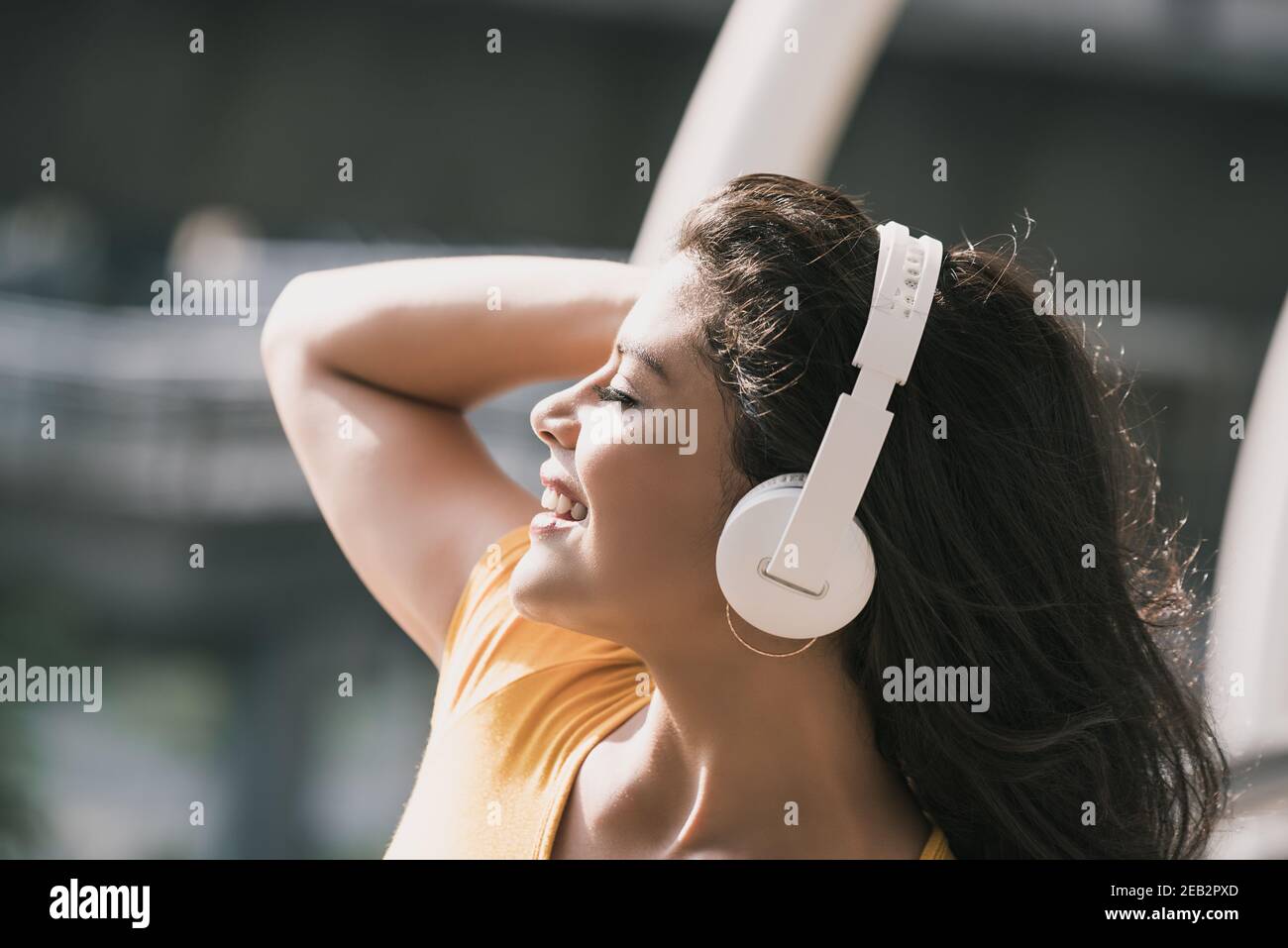 Jeune femme hispanique heureuse portant un casque qui écoute de la musique avec yeux fermés Banque D'Images