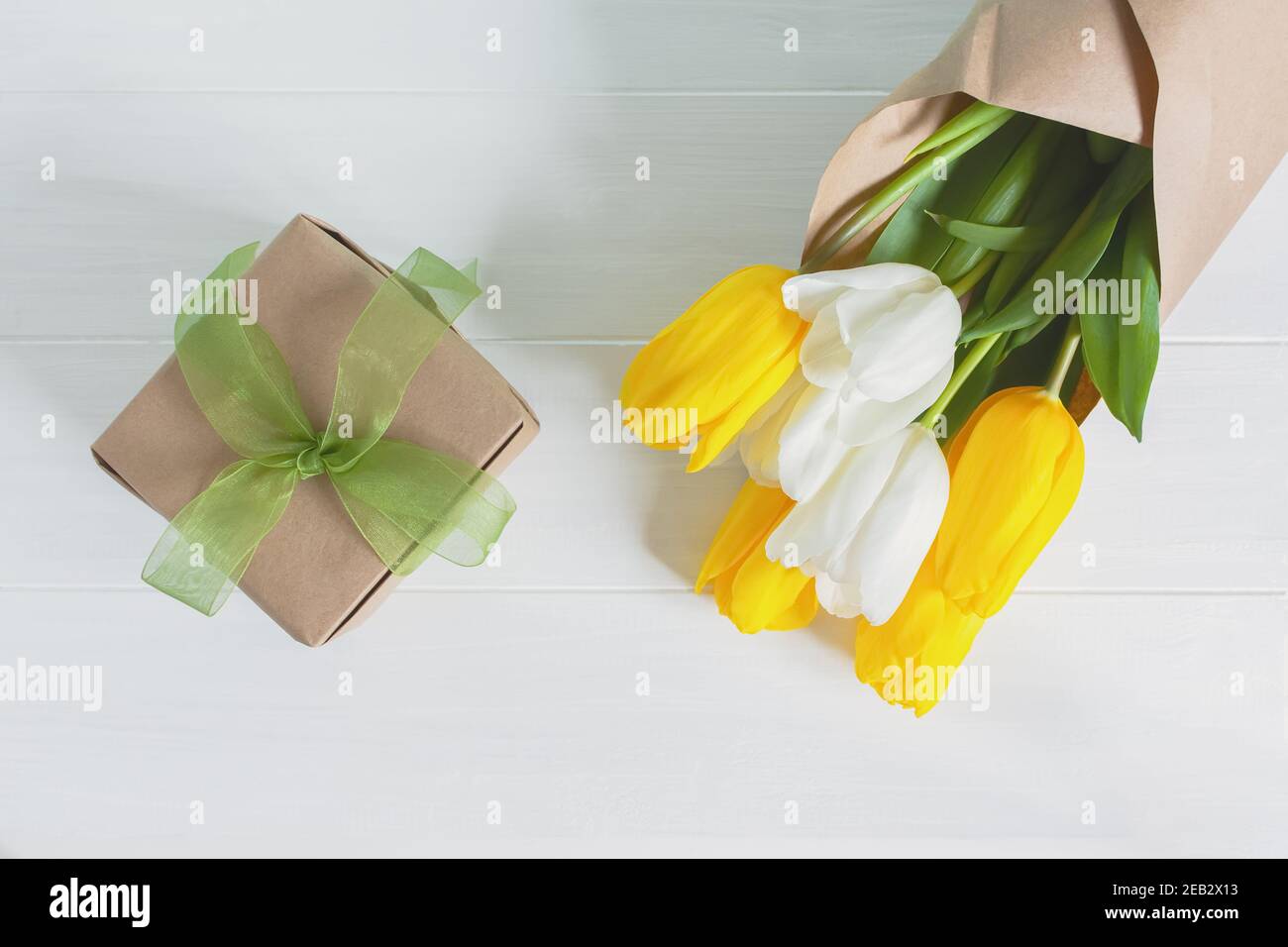 Tulipes jaunes et blanches sur fond de bois clair. Cadeau et bouquet en papier kraft. Le concept de la Journée internationale de la femme, 8 mars, 1 jour de spr Banque D'Images