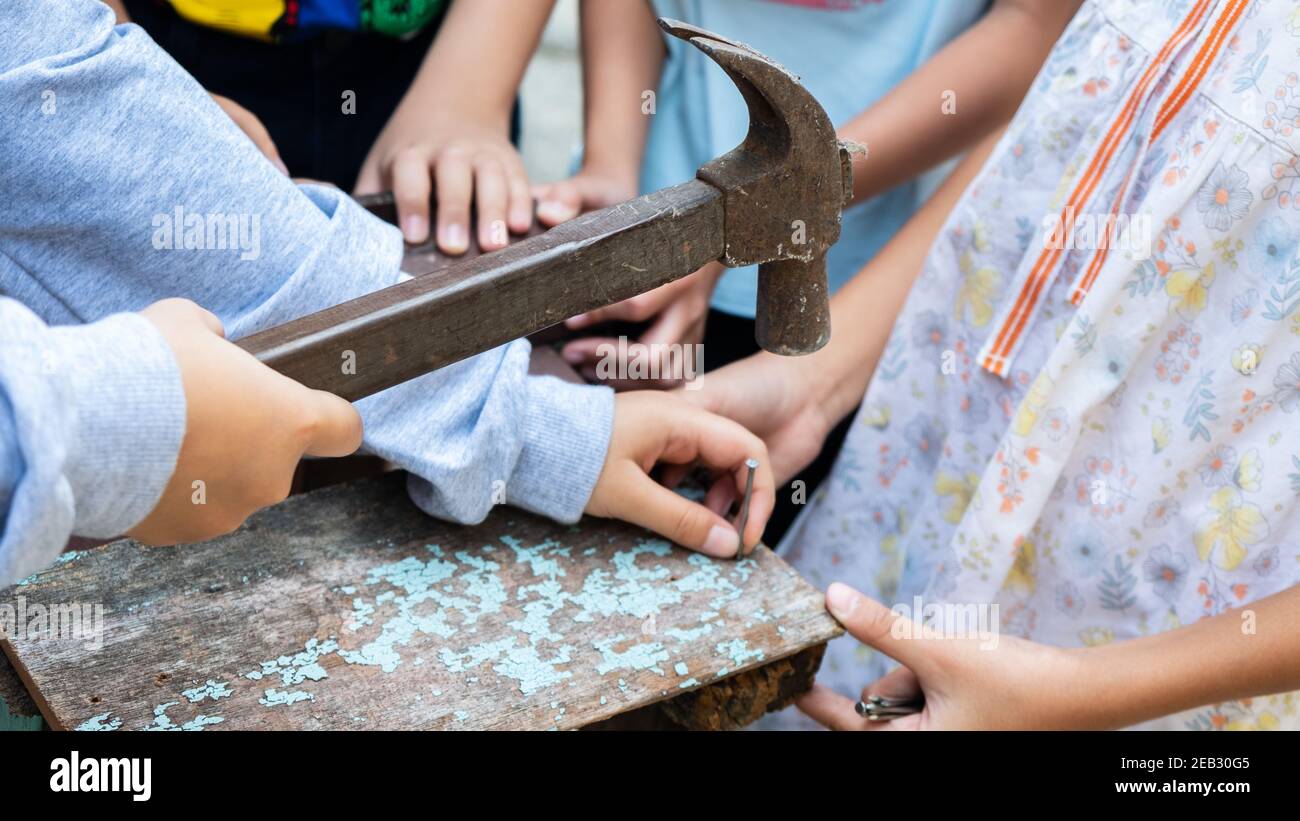 Les enfants réparent le bois avec des clous et un marteau Banque D'Images