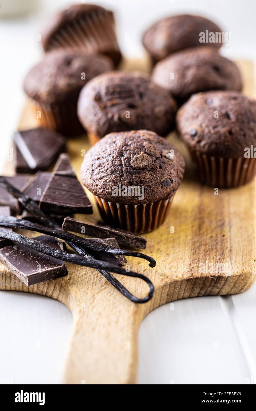 Muffins au chocolat. Petits gâteaux doux et foncés avec gousses de chocolat et de vanille sur planche à découper. Banque D'Images