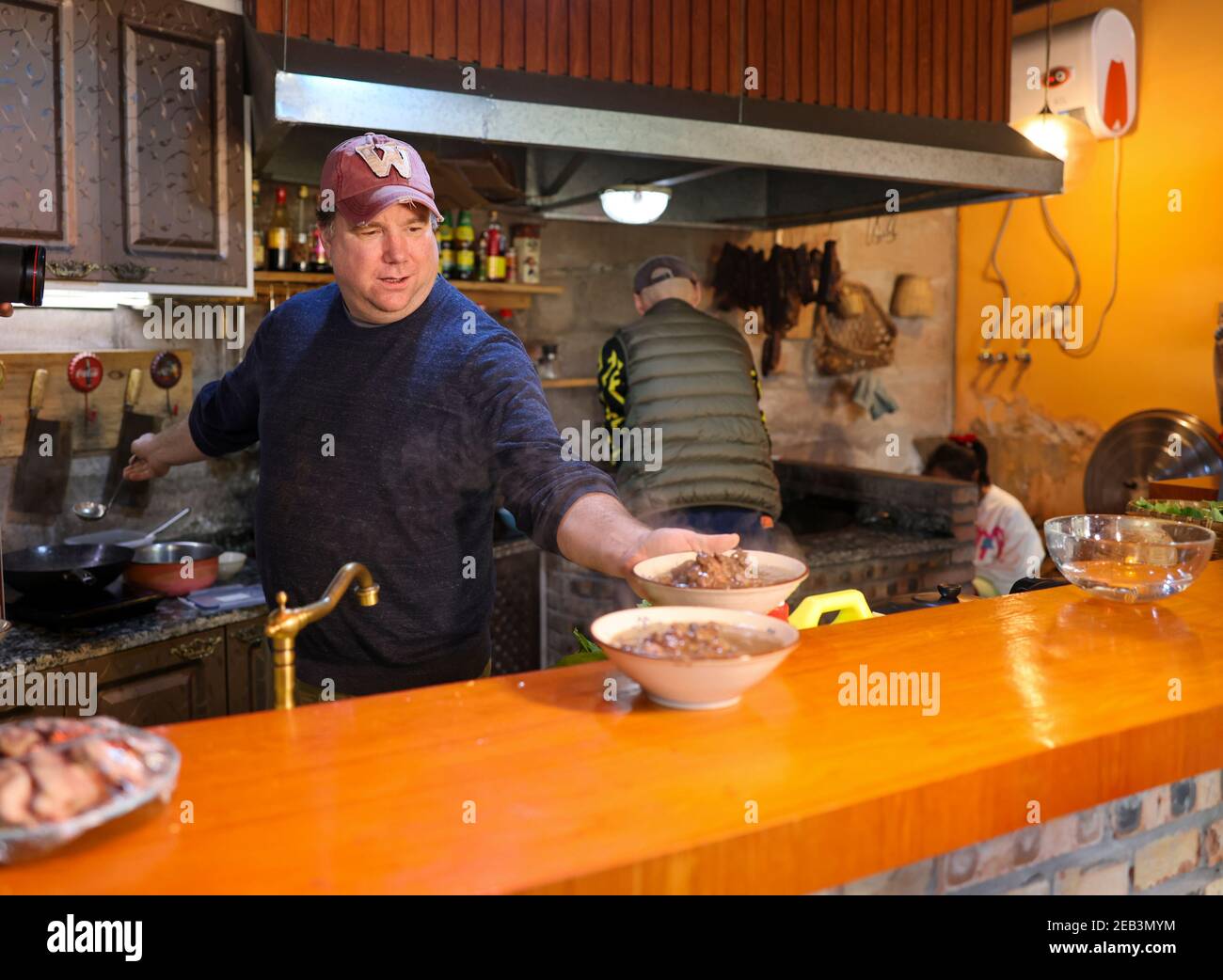 (210212) -- CHONGQING, le 12 février 2021 (Xinhua) -- Benjamin cuisine dans la cuisine pour un festin pour accueillir le nouvel an lunaire chinois à Chongqing, dans le sud-ouest de la Chine, le 10 février 2021. Benjamin, un américain vivant à Chongqing, dans le sud-ouest de la Chine, est aujourd'hui une célébrité de l'Internet avec plus de 900 000 adeptes sur les médias sociaux. Benjamin aime le hot pot de Chongqing, peut faire le jeu de devinettes traditionnel de Chongqing et peut parler couramment le dialecte de Chongqing. Ses clips vidéo sur la vie à Chongqing sont passés au mode viral en ligne. En 1994, Benjamin est venu à Chongqing pour étudier. Plus tard, il est devenu professeur d'anglais au Sichuan Banque D'Images