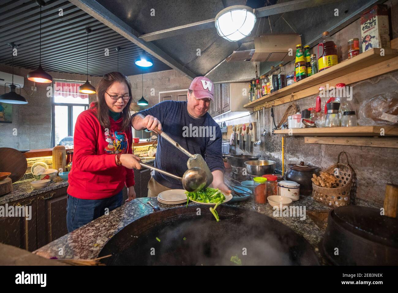 (210212) -- CHONGQING, le 12 février 2021 (Xinhua) -- Benjamin cuisine dans la cuisine pour un festin pour accueillir le nouvel an lunaire chinois à Chongqing, dans le sud-ouest de la Chine, le 10 février 2021. Benjamin, un américain vivant à Chongqing, dans le sud-ouest de la Chine, est aujourd'hui une célébrité de l'Internet avec plus de 900 000 adeptes sur les médias sociaux. Benjamin aime le hot pot de Chongqing, peut faire le jeu de devinettes traditionnel de Chongqing et peut parler couramment le dialecte de Chongqing. Ses clips vidéo sur la vie à Chongqing sont passés au mode viral en ligne. En 1994, Benjamin est venu à Chongqing pour étudier. Plus tard, il est devenu professeur d'anglais au Sichuan Banque D'Images