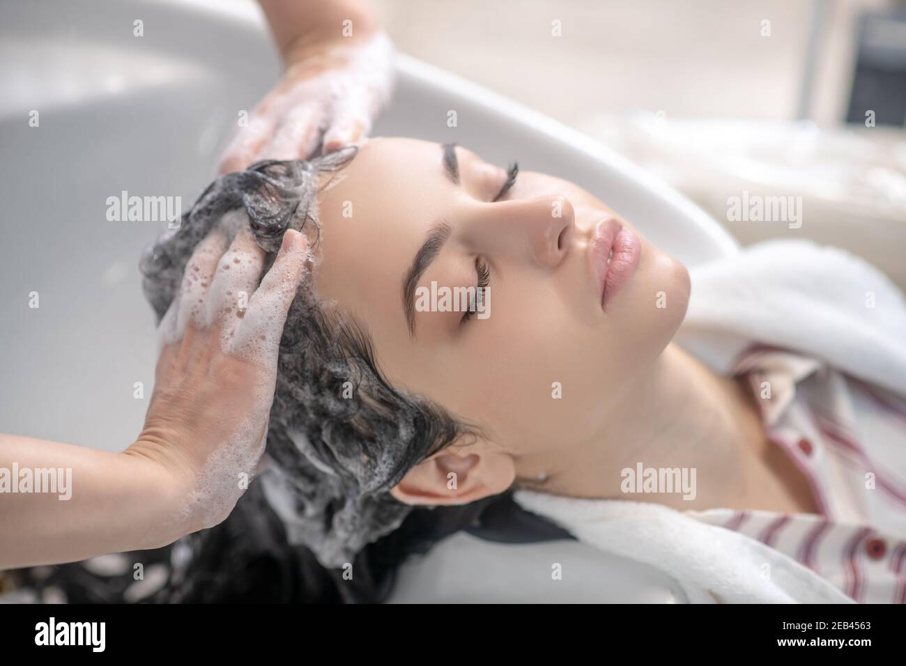 Coiffeur coiffant ses clients cheveux avec shampooing Banque D'Images