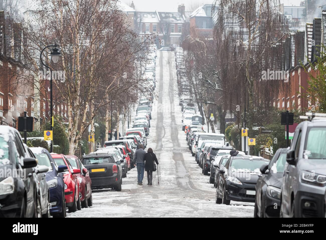 Un couple qui monte dans une rue couverte de neige dans le quartier de Crouch End, dans le nord de Londres Banque D'Images
