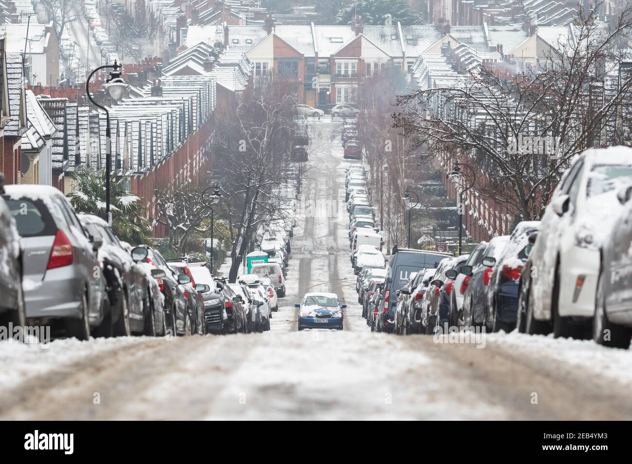 Londres, Royaume-Uni - 9 février 2021 - UNE voiture qui monte sur une route enneigée dans le Crouch End, dans des conditions de conduite difficiles Banque D'Images