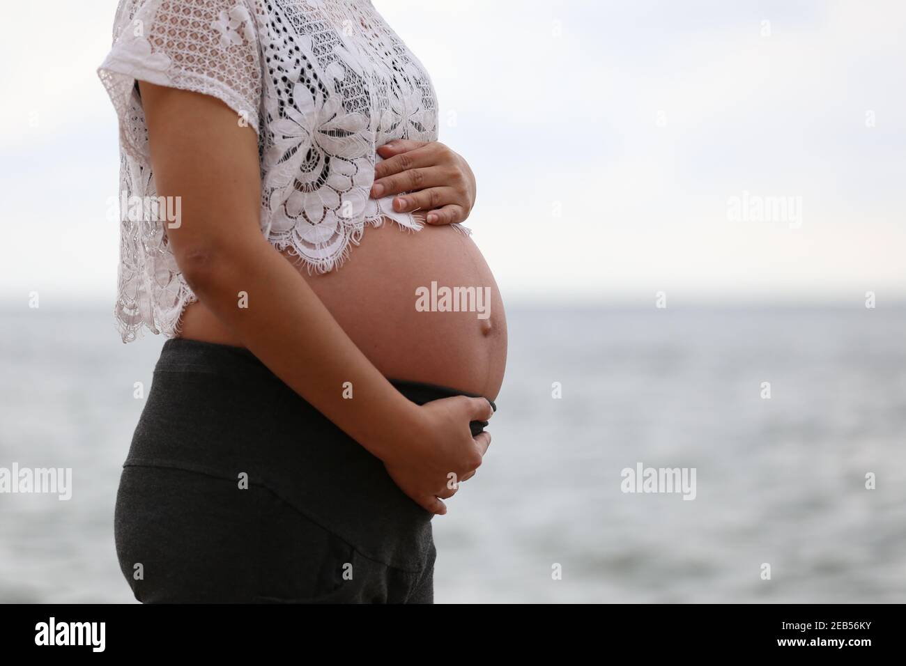Femme enceinte dans une robe bleue sur la mer et le ciel flou d'arrière-plan et ont l'espace de copie. Banque D'Images