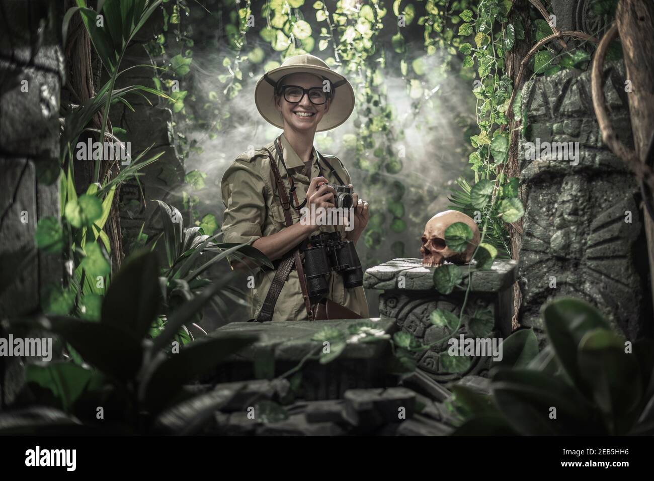 Femme courageuse explorant la jungle et prenant des photos avec son appareil photo, elle trouve des ruines antiques et un crâne humain Banque D'Images