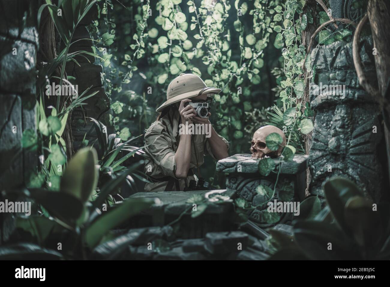 Femme courageuse explorant la jungle et prenant des photos avec son appareil photo, elle trouve des ruines antiques et un crâne humain Banque D'Images