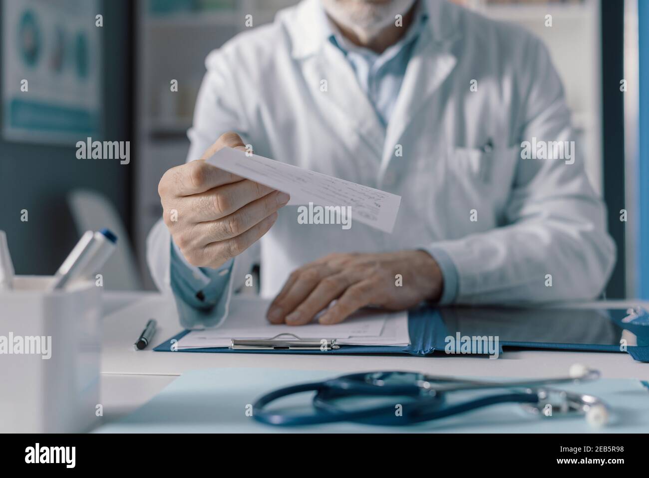 Médecin professionnel travaillant dans son bureau, il donne une ordonnance à son patient, point de vue Banque D'Images