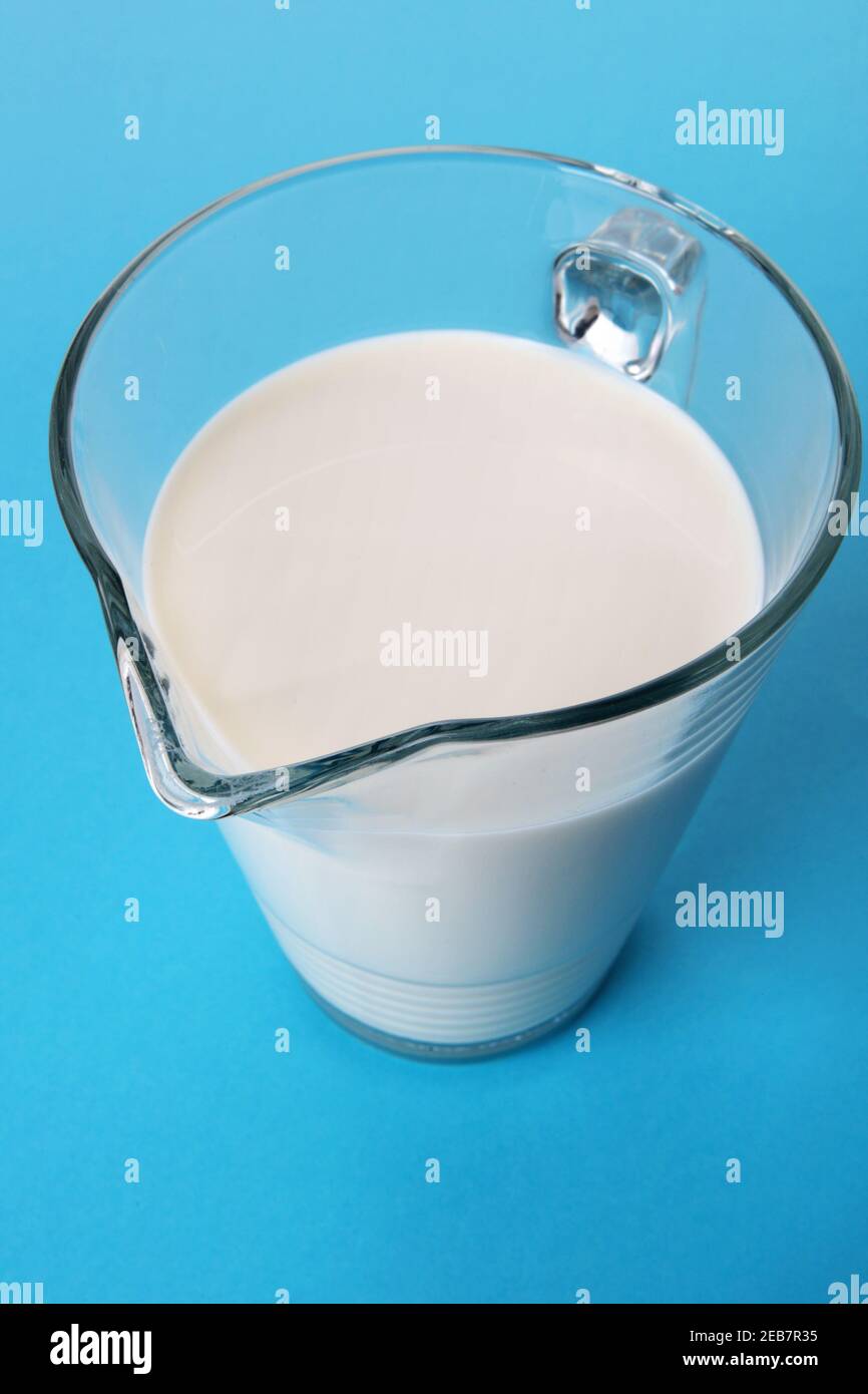 Carafe en verre contenant du lait frais isolée sur fond bleu avec ombre. Vue grand angle Banque D'Images