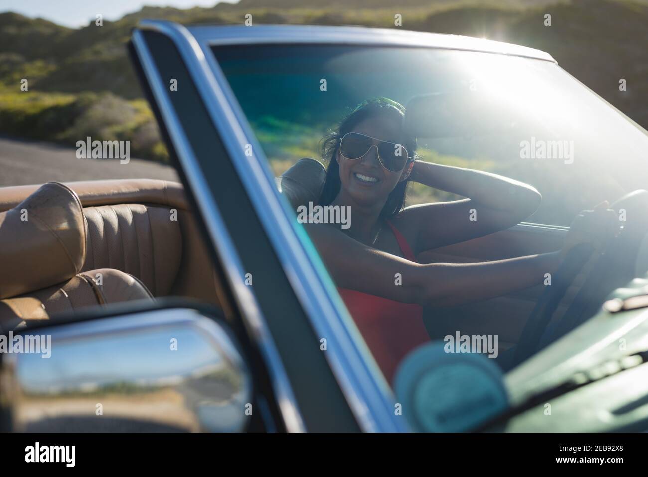 Femme de course mixte conduite par beau temps dans une voiture décapotable maintien de la roue motrice Banque D'Images