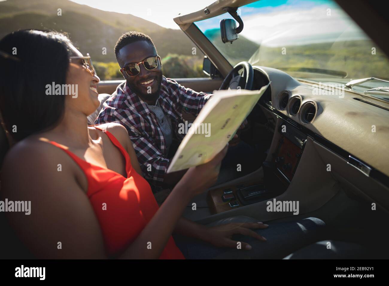 Couple varié par beau temps assis dans une voiture décapotable sur une carte Banque D'Images