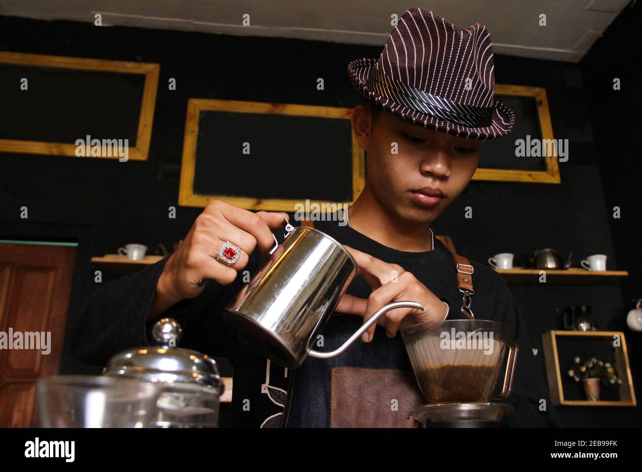 Le Barista indonésien prépare des cafés pour les clients au café. Portrait d'un employé du café au bar. Le processus de Banque D'Images