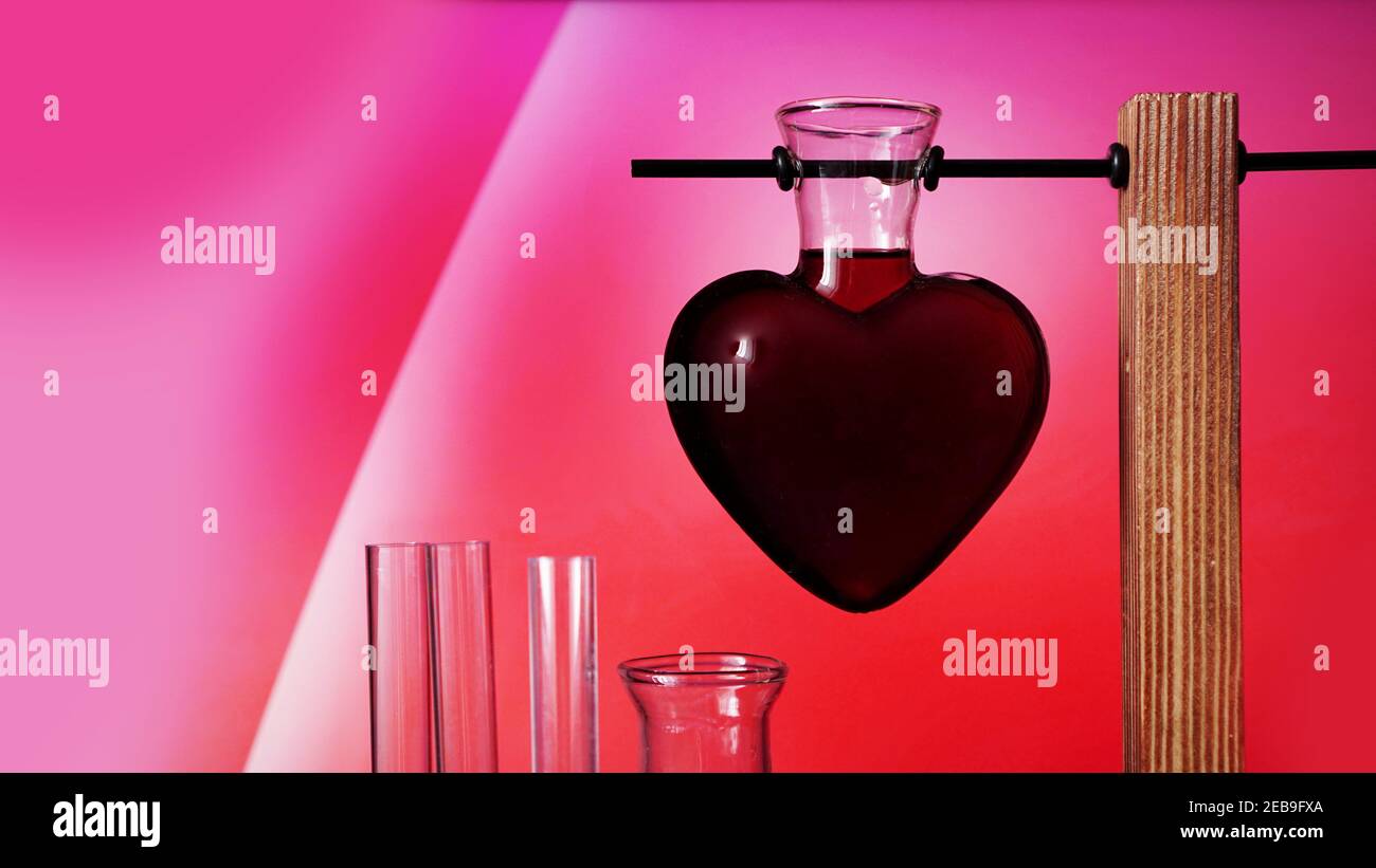 Potion Saint-Valentin. Potion d'amour en forme de coeur sur fond rose. Flacons de produits chimiques. Banque D'Images