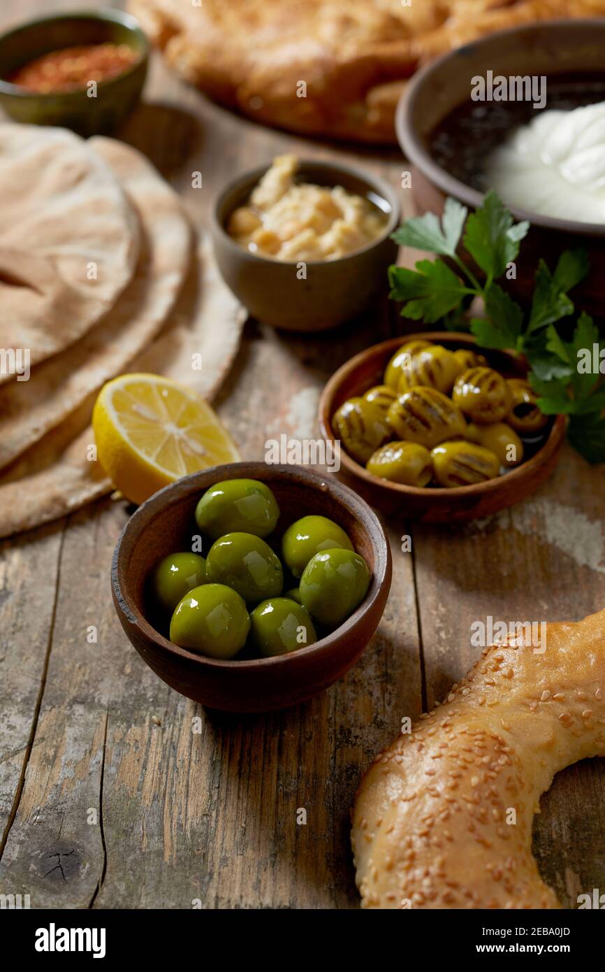 Bagel de sésame frais aux olives vertes méditerranéennes, mozzarella, tartinade aux pois chiches et pain plat pour un petit déjeuner sain servi sur un bois rustique Banque D'Images