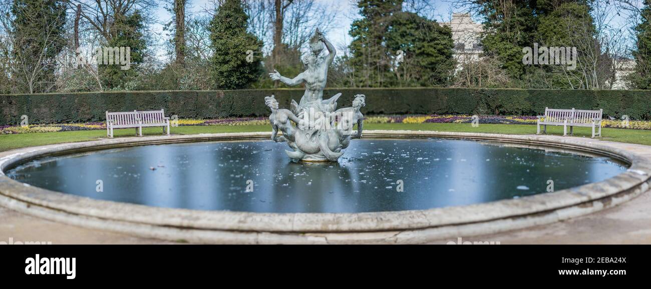 Vue panoramique d'une fontaine Triton qui est un groupe de sculptures en bronze représentant un dieu marin soufflant sur une coquille de conch avec deux mermaids à ses pieds. Banque D'Images