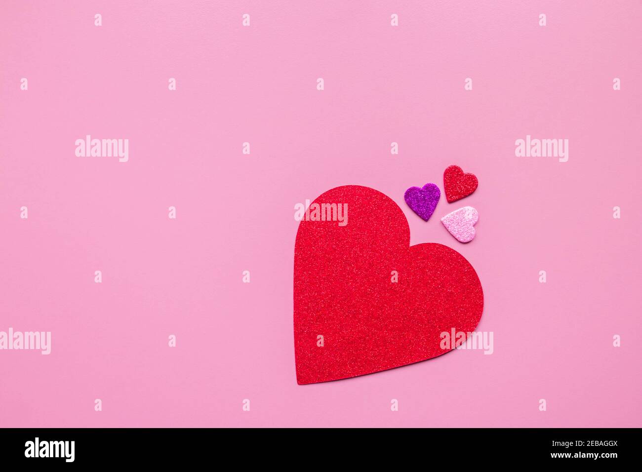 Un grand coeur et un petit coeur de papier rouge, rose, violet et violet sur fond rose avec espace de copie. Contexte de la Saint-Valentin. Saint Valentin. À Banque D'Images