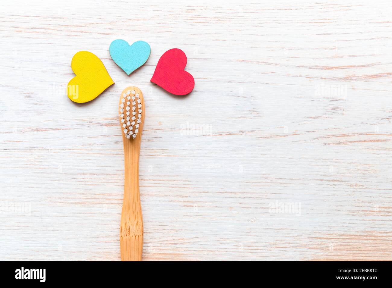Brosse à dents en bambou naturel et coeurs en bois sur fond de bois. Brosse à dents en bambou biodégradable. Produit de bain naturel. Zéro déchet, écologique, plastique Banque D'Images