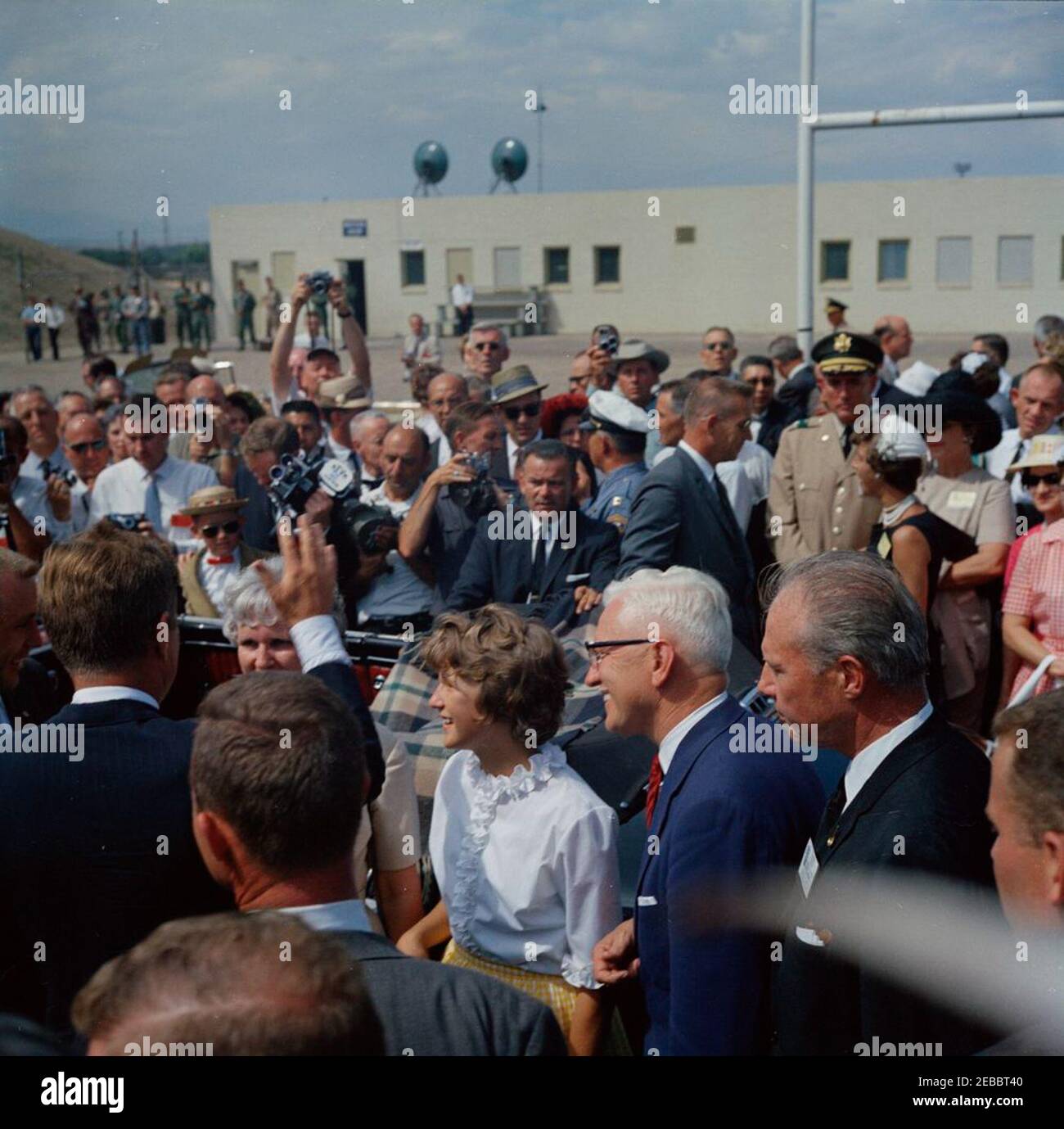 Voyage dans les États de l'Ouest : Pueblo, Colorado, 12:50. Le président John F. Kennedy (à gauche, avec le retour à la caméra) fait des vagues vers les visiteurs à Pueblo, au Colorado; le président Kennedy s'est rendu au Colorado pour commémorer le projet de remise en état de Fryingpan-Arkansas. Le gouverneur du Colorado, Stephen L. R. McNichols, se trouve à droite. Aussi en photo : les agents du Service secret de la Maison Blanche, Jerry Blaine, Hank Rybka, Arthur L. u0022Artu0022 Godfrey et Ron Pontius. Banque D'Images