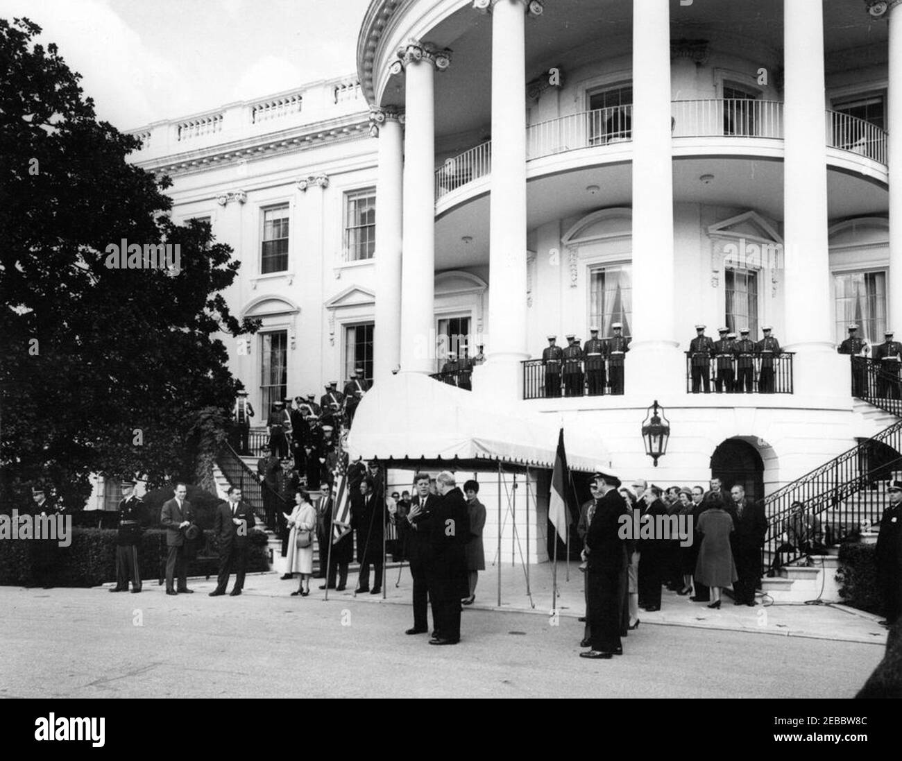 Cérémonies d'arrivée pour Konrad Adenauer, chancelier de l'Allemagne de l'Ouest, 10:45. Le président John F. Kennedy (au centre à gauche en premier plan) s'entretient avec le secrétaire d'État des États-Unis, Dean Rusk, avant l'arrivée du chancelier de l'Allemagne de l'Ouest, M. Konrad Adenauer, à la Maison Blanche. Également en photo : la première dame Jacqueline Kennedy; le président des chefs d'état-major interarmées, le général Maxwell D. Taylor; l'aide navale au président, le capitaine Tazewell Shepard; l'ambassadeur du Nicaragua et doyen du corps diplomatique, le Dr Guillermo Sevilla-Sacasa; le chef adjoint des services linguistiques au département d'État, interprète Banque D'Images