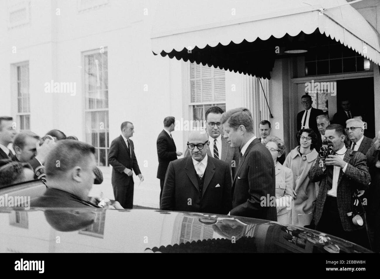 Rencontre avec Ramon Villeda Morales, président du Honduras, 11 heures DU MATIN. Le Président John F. Kennedy accompagne le Président de la République du Honduras, M. Ramu00f3n Villeda Morales (au centre), dans sa voiture, à la suite des cérémonies d'arrivée et d'une réunion à la Maison Blanche. Fernando van Reigersberg, interprète du département d'État des États-Unis, se tient derrière les présidents; l'ambassadeur de la République du Honduras, le Dr Cu00e9leo Du00e1vila, se tient à droite en arrière-plan; des photographes et des reporters non identifiés observent. Entrée de l'aile ouest, Maison Blanche, Washington, D.C. Banque D'Images