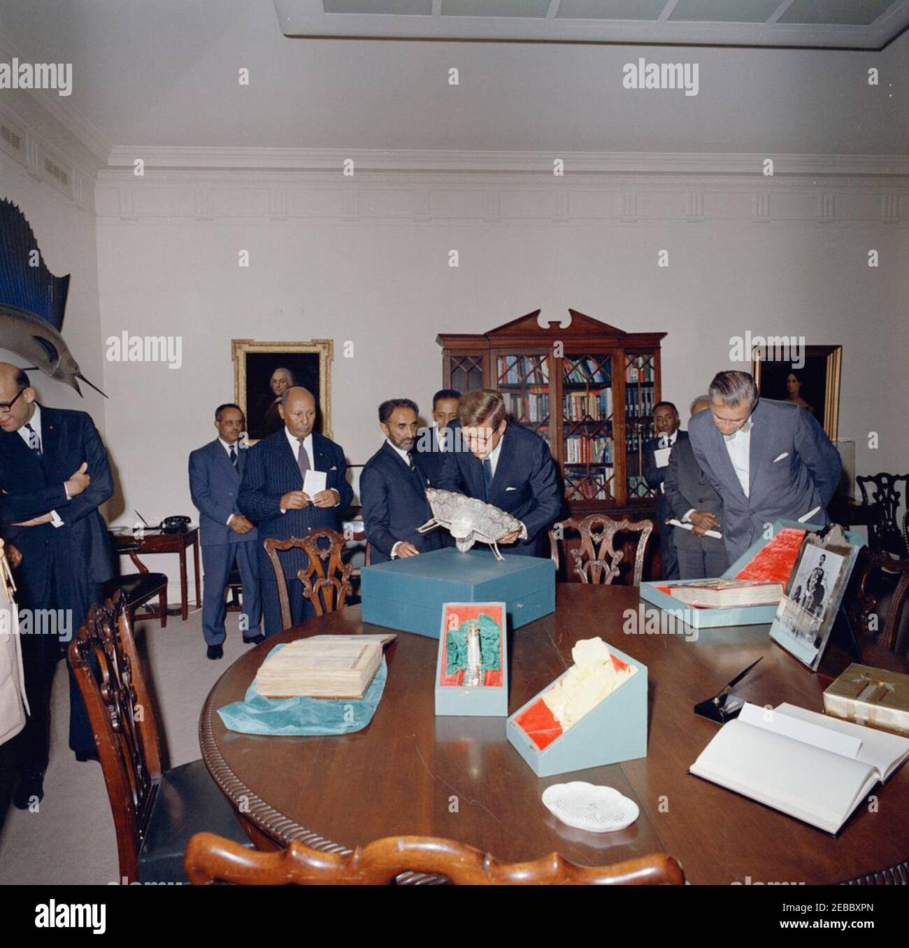 Rencontre avec Haile Selassie I, empereur d'Éthiopie, 4:00. Le président John F. Kennedy (portant des lunettes) regarde un bol en filigrane lors d'un échange de cadeaux avec l'empereur d'Éthiopie, Haile Selassie I, dans la salle des poissons de la Maison Blanche. De gauche à droite : l'ambassadeur des États-Unis en Éthiopie, Edward M. Korry; non identifié; le ministre de la Cour impériale d'Éthiopie, Tafarra-Worq Kidane-Wold; l'empereur Selassie; non identifié (à l'arrière); le président Kennedy; le ministre des Finances de l'Éthiopie, Yilma Deressa (à l'arrière); Imru Haile Selassie (pour la plupart caché), second cousin de l'empereur Selassie; le secrétaire adjoint des États-Unis Banque D'Images