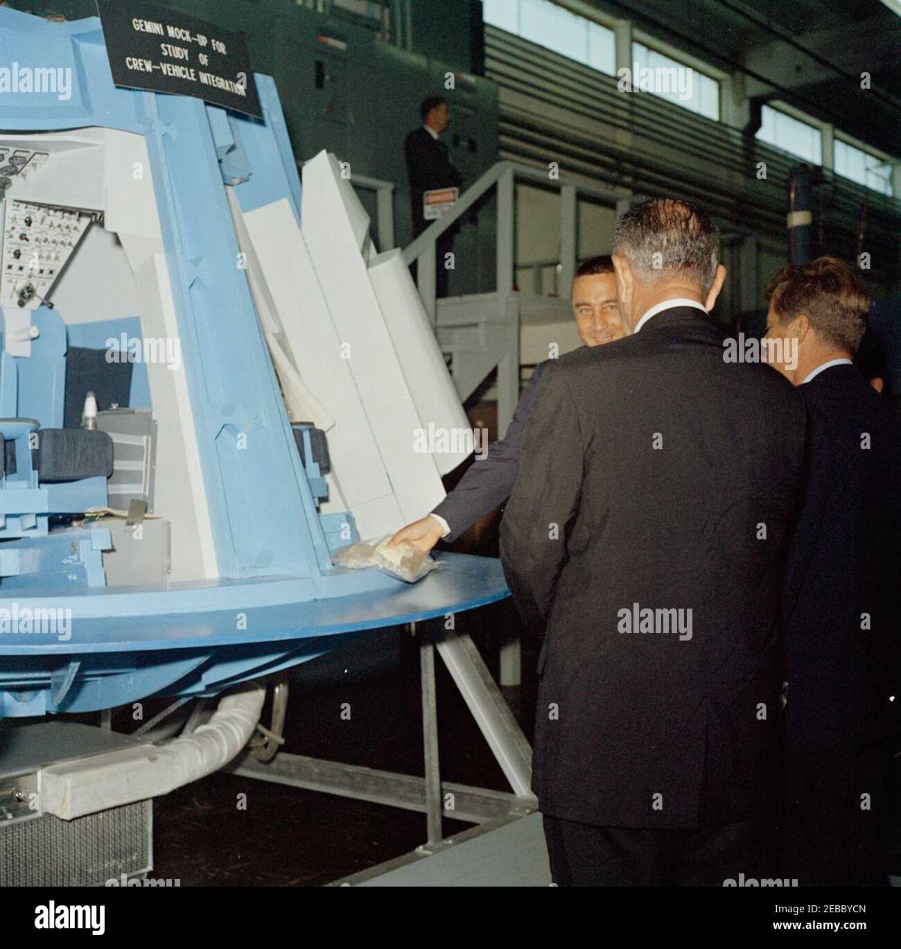 Visite d'inspection des installations de la NASA : Houston, Texas, NASA Rich Building, départ, 11:10. Le président John F. Kennedy et le vice-président Lyndon B. Johnson (tous deux avec dos à la caméra) voient une maquette de l'intérieur d'une capsule Gemini, lors d'une visite d'expositions d'engins spatiaux à l'intérieur d'un hangar au bâtiment riche du centre spatial habité de Houston, Texas; L'astronaute Major Virgile I. u201cGusu201d Grissom fait une présentation au Président Kennedy et au Vice-Président Johnson. Le Président a visité le Centre dans le cadre d'une visite d'inspection de deux jours de l'Institut national de l'aéronautique et de l'espace (NASA) Banque D'Images