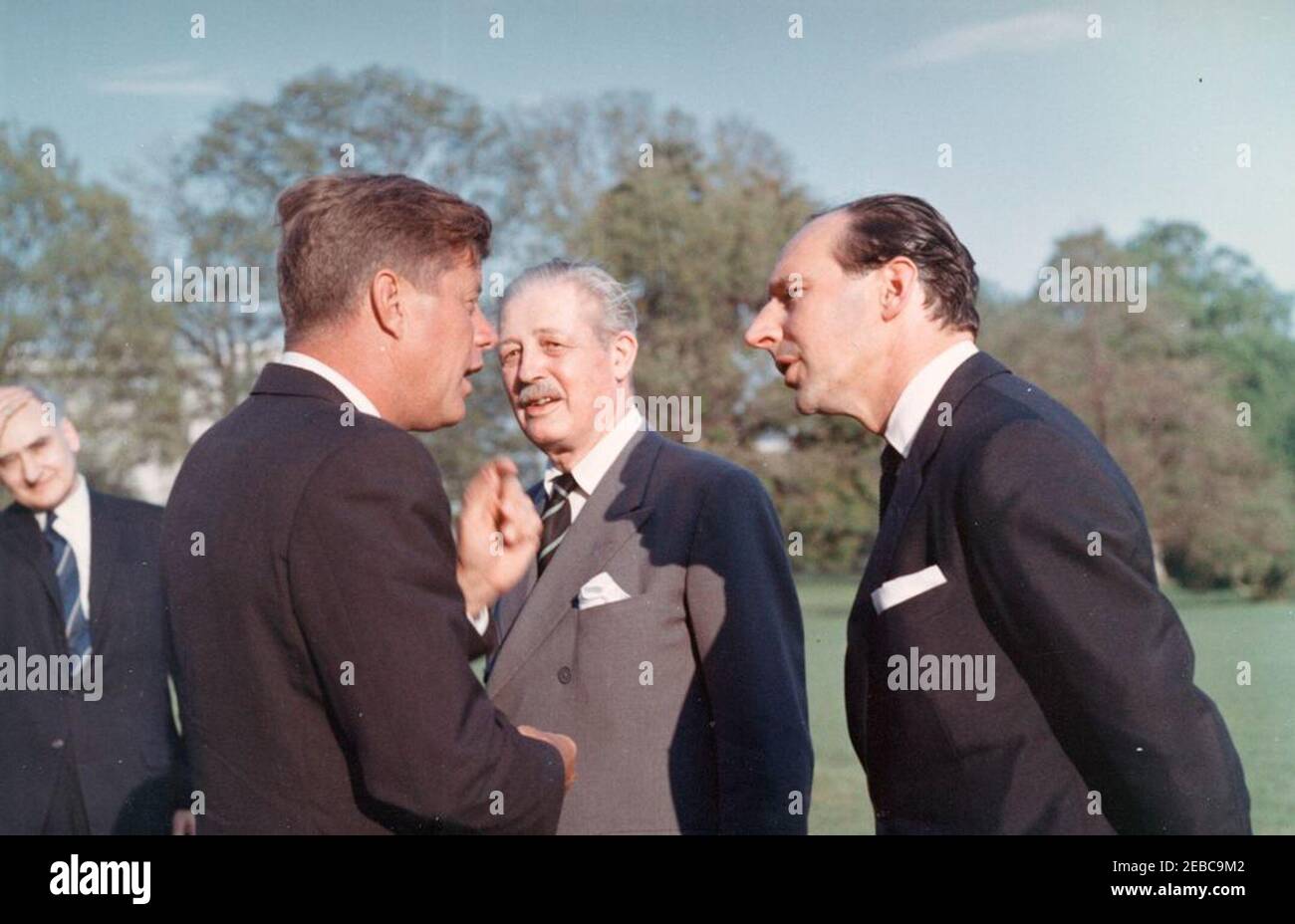 Cérémonies d'arrivée pour Harold Macmillan, Premier ministre de Grande-Bretagne, 4 h 50. Le président John F. Kennedy s'entretient avec le Premier ministre de la Grande-Bretagne, Harold Macmillan (au centre), et l'ambassadeur de la Grande-Bretagne, Sir David Ormsby-Gore (à droite), après leur arrivée à la Maison Blanche depuis la base aérienne d'Andrews, Maryland. Le chef adjoint du Protocole, William J. Tonesk, est à l'arrière-plan, à l'extrême gauche. South Lawn, Maison Blanche, Washington, D.C. Banque D'Images