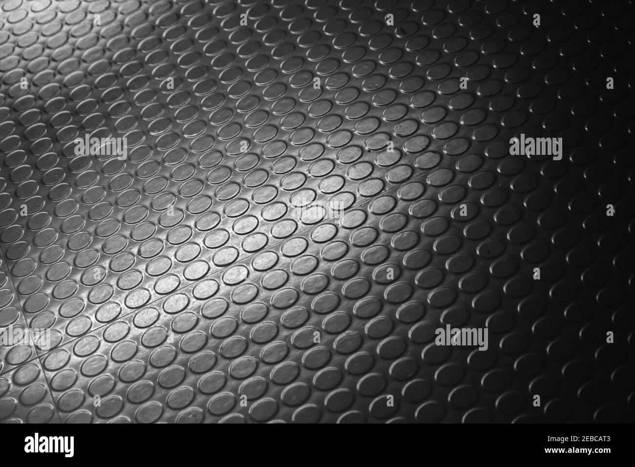 Relief de tapis en caoutchouc noir brillant et pointillé. Photo d'arrière-plan avec mise au point douce sélective Banque D'Images