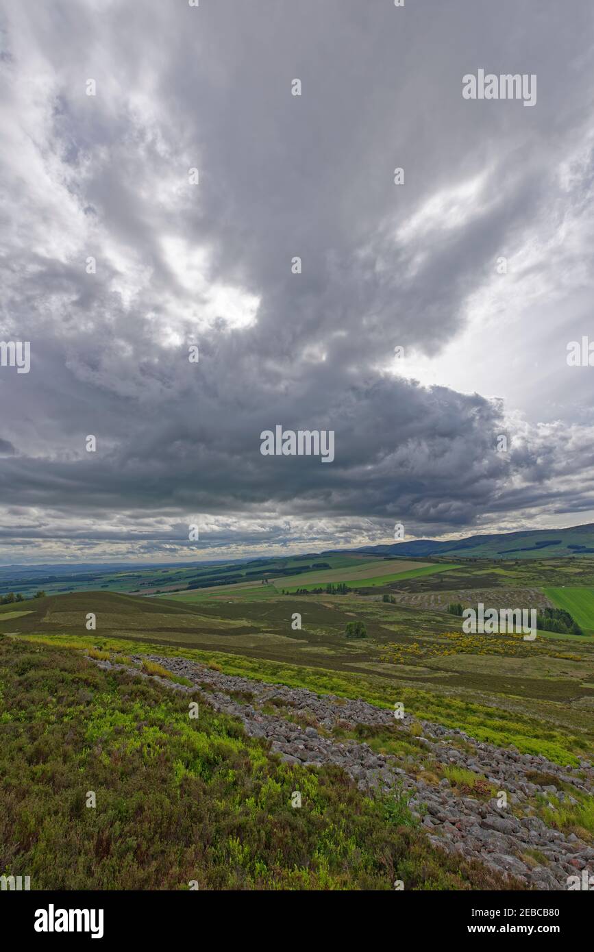 Vue vers le sud sur les vestiges des remparts de pierre de la Traitthun blanc à l'Angus Glens avec des nuages sombres d'un front de temps au-dessus. Banque D'Images