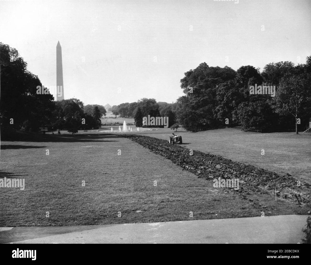 Labourage de la pelouse du Sud. Un travailleur sur un tracteur ploige une section de la pelouse sud en vue de l'installation d'un système sprinkleur. Le Washington Monument et le Lincoln Memorial sont visibles en arrière-plan. Washington, D.C. Banque D'Images