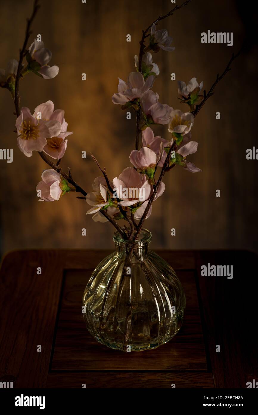Bouquet de fleurs roses printanières dans un vase en verre isolé sur fond de bois. Banque D'Images