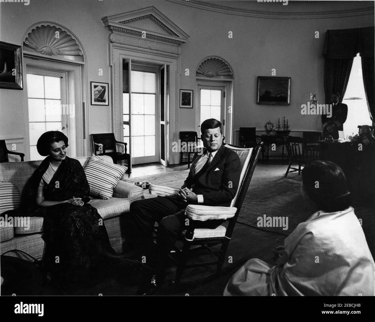 Rencontre avec Indira Gandhi, 11:00. Le président John F. Kennedy (président à bascule) rencontre Indira Gandhi, fille du Premier ministre indien Jawaharlal Gandhi (assis sur un canapé), et Shobha Nehru (également connu sous le nom de Fori Nehru), épouse de l'ambassadeur indien aux États-Unis, Braj Kumar Nehru. L'aide navale au Président Tazewell Shepard est en arrière-plan. Oval Office, Maison Blanche, Washington, D.C. Banque D'Images